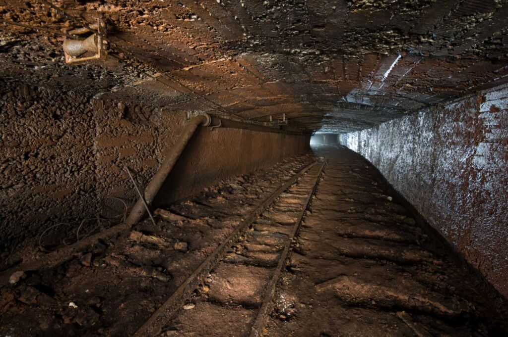 Der breite Förderstollen / Ausweichstrecke mit Gegenlicht. Am Boden existiert noch ein Gleis von ehemals drei.