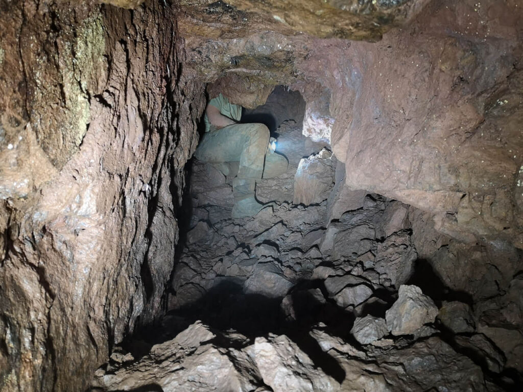 Person, die auf einem Schuttkegel im Stoll sitzt