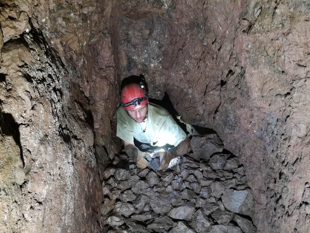 Person, die im Stollen auf Geröll liegt