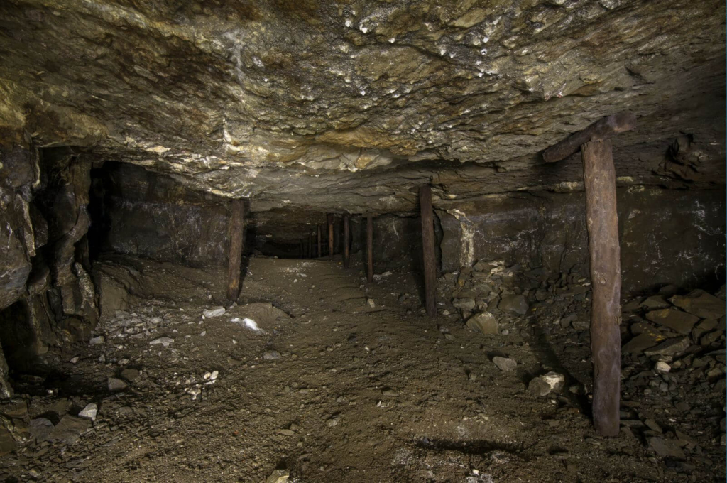 Flache Förderstrecke im Abbau mit Holzstempel zur Sicherung der Firste.