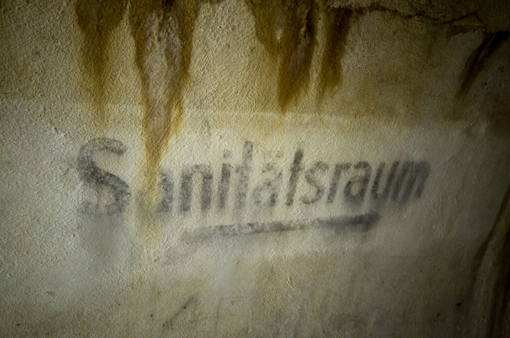 Wegweiser an der Wand mit Pfeil unter der Beschriftung "Sanitätsraum".