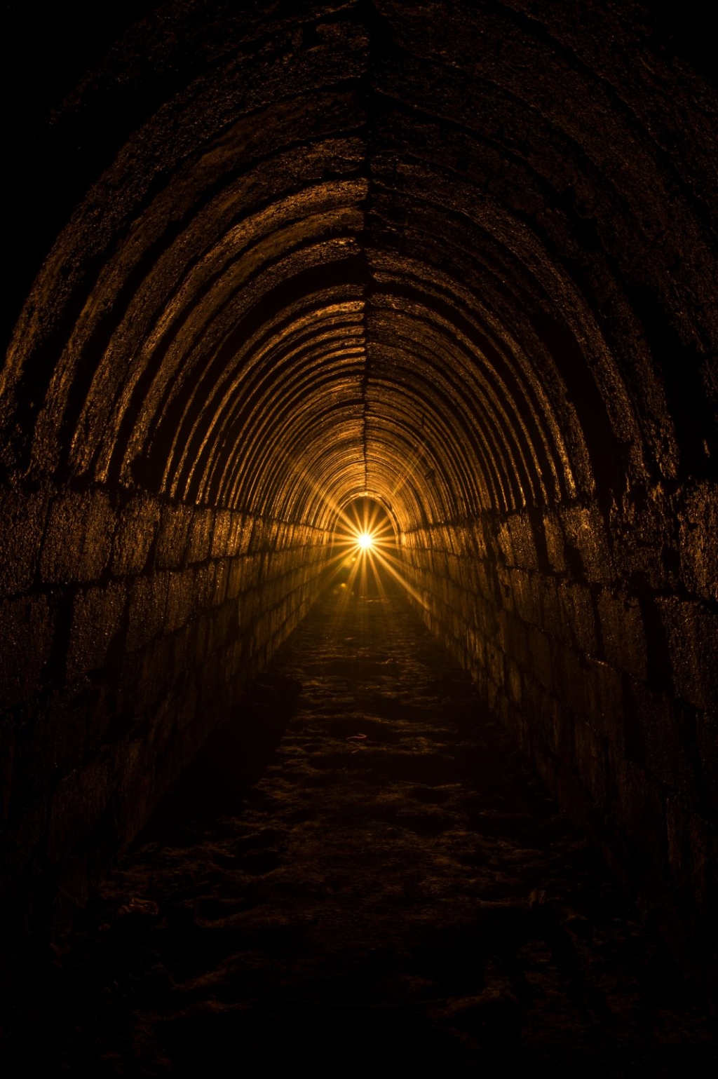 004-werkluftschutzstollen-himmelsbuckel Zeigt den langen dunklen Luftschutzstollen mit einem hellen Gegenlicht, das einen goldenen Stern bildet.