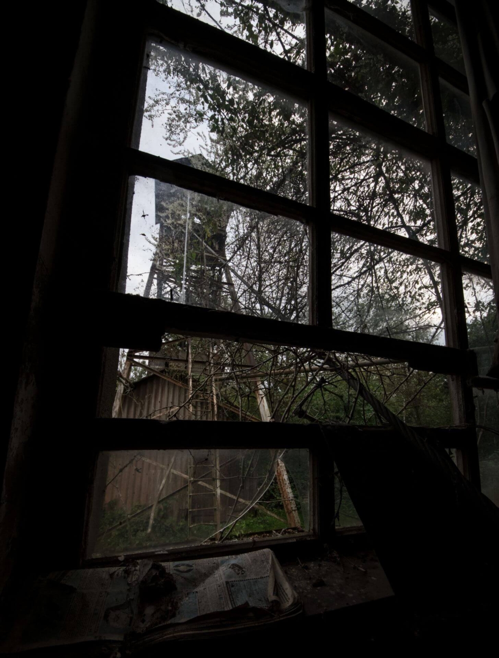 Blick durch das Fenster des Fördermaschinenraums auf den stählernen Förderturm.