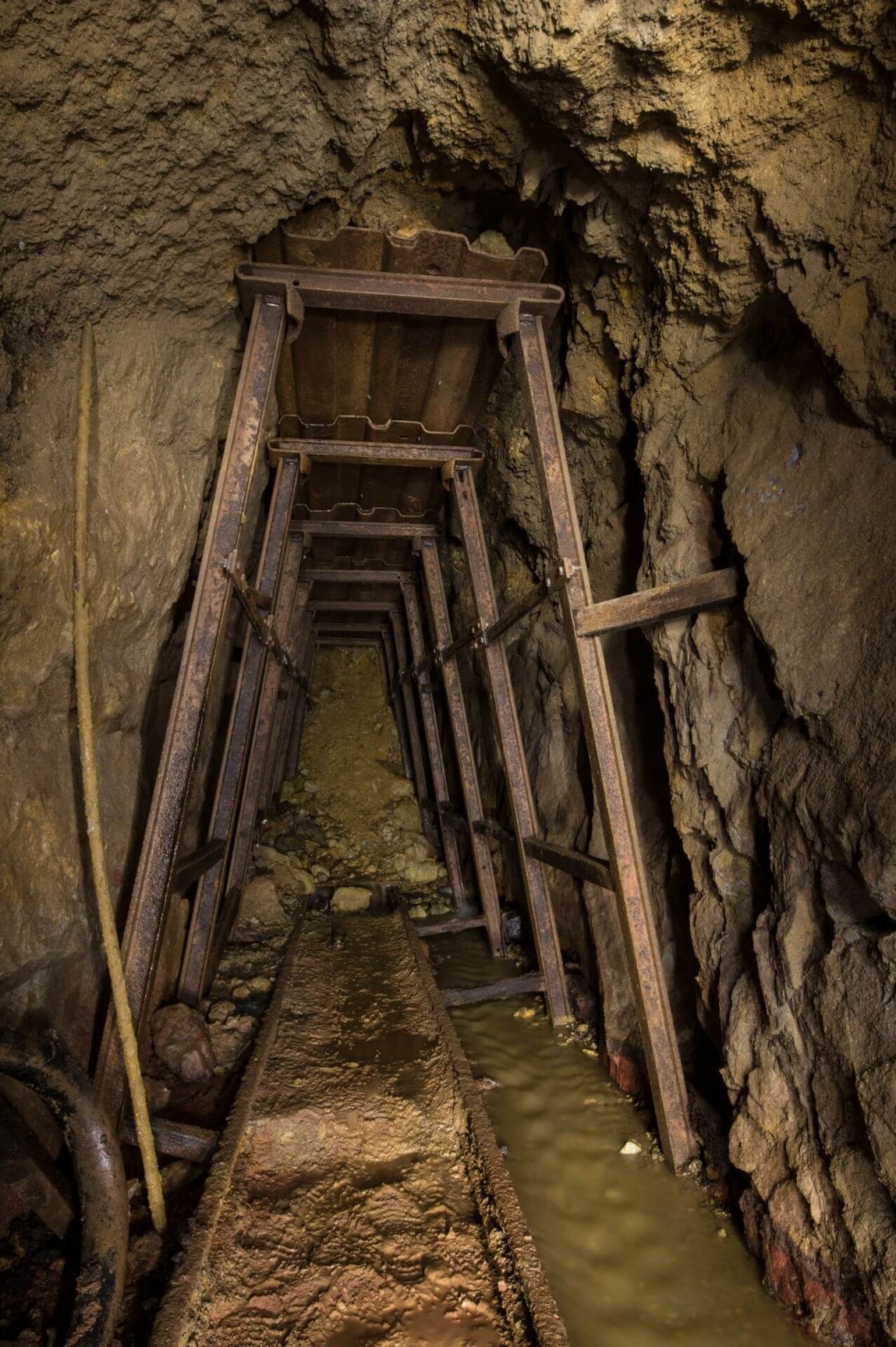 Zeigt einen massiven Stahlausbau am heutigen Ende des Wasserlösestollens. Am Ende ist der Stollen verbrochen. Nur das Wasser fließt unten rechts durch.