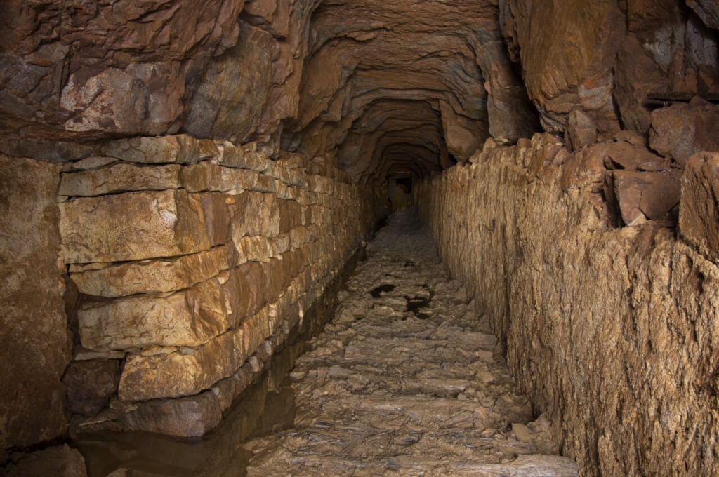 008-tortenstollen Zeigt den Hauptstollen mit einer Steinquadermauer auf der linken Seite und einer glatten Mauer auf der rechten Seite.