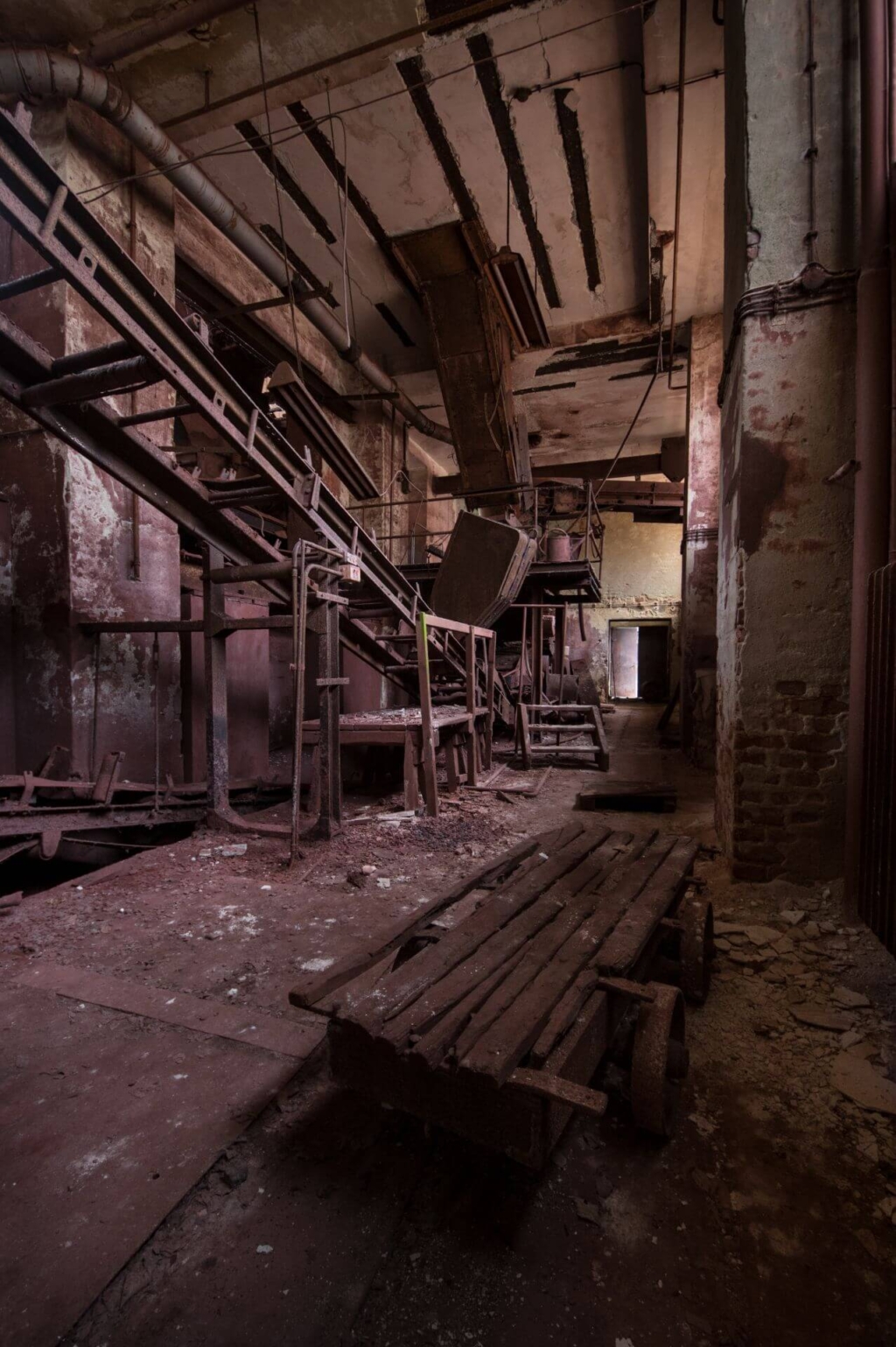 Zeigt die Halle der Erzaufbereitung mit seinen roten Wänden. Im Vordergrund ein kleiner Förderwagen