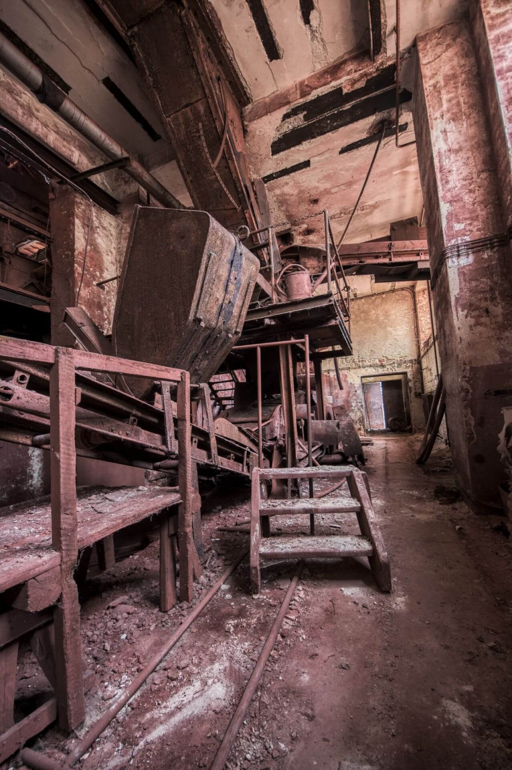 Zeigt die Halle der Erzaufbereitung mit seinen roten Wänden. Links das Förderband mit Kippmulde.