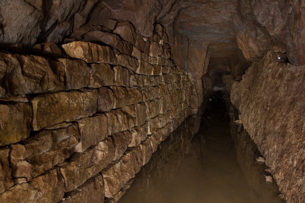 013-tortenstollen Zeigt den Hauptstollen, in dem 20 cm Wasser steht. Links eine Trockenmauer aus Steinquadern.
