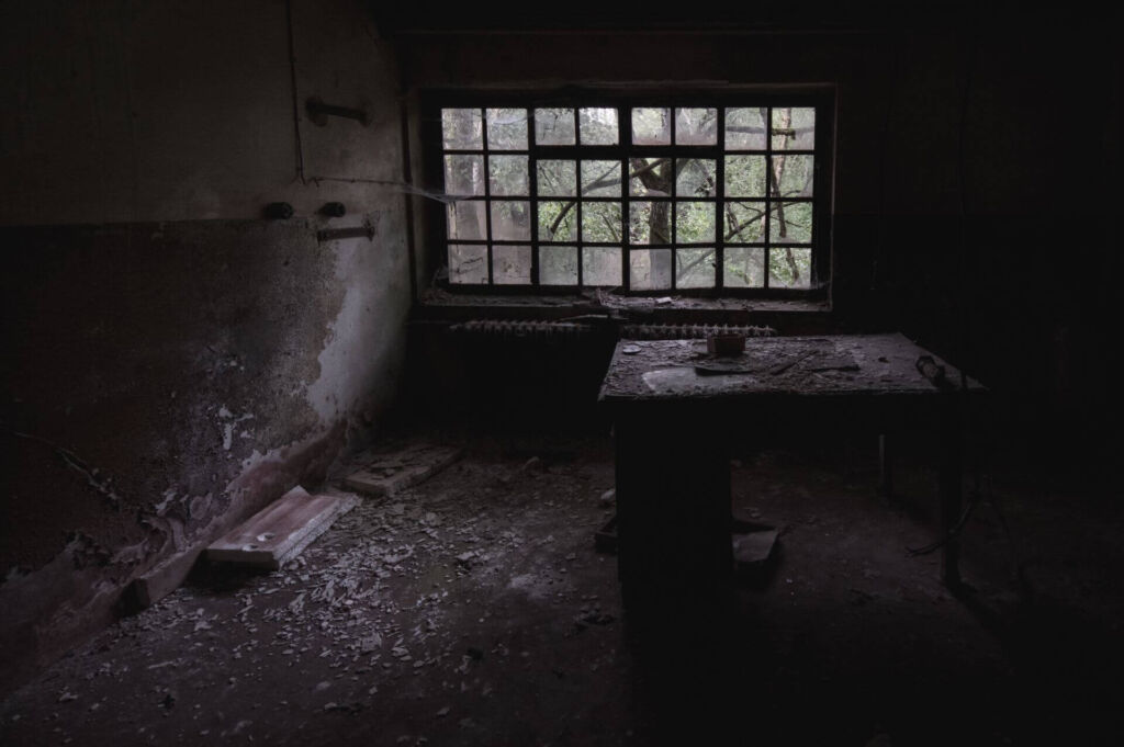 Dunkler Büroraum mit altem Schreibtisch in der Mitte des Raums.