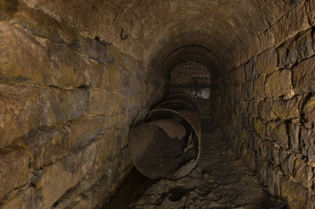 017-tortenstollen Zeigt das ehemalige Mundloch von Innen. links liegen rostige Leitungen der Bewetterung.