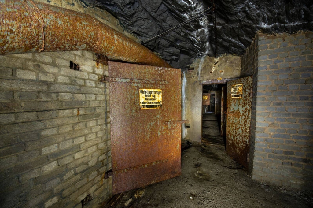 Zeigt einen langen Gang im Sprengstoffbunker der Grube mit mehreren Türen zu den Sprengkammern.