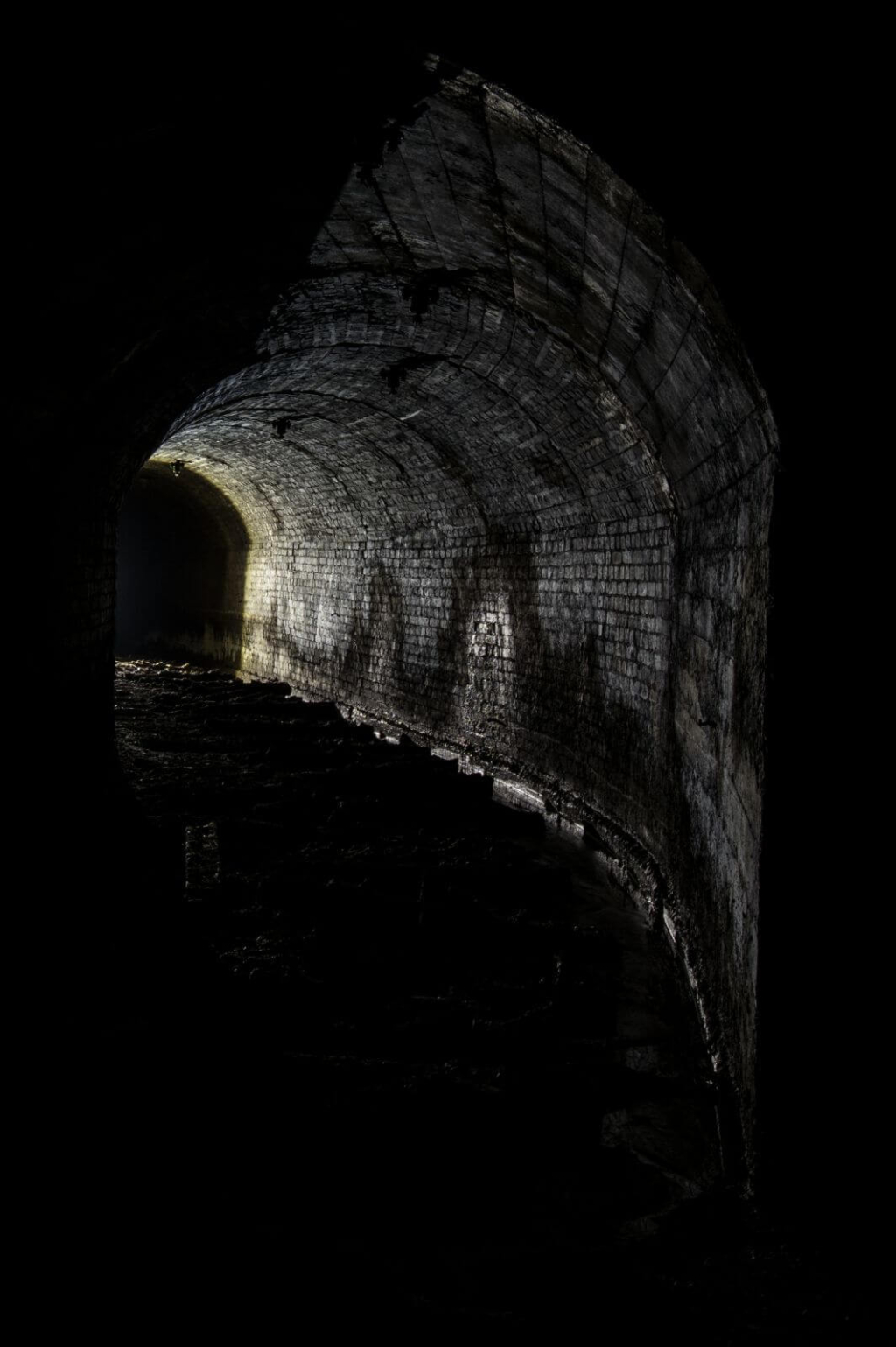 Zeigt einen Streckenabschnitt im Gegenlicht. Der Ausbau besteht aus Ziegel und die Decke ist rund.