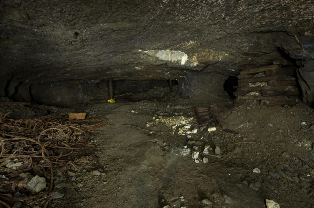 Zeigt einen großen Abbau im Erzkörper. Rechts ein Holzkastenpfeiler, welcher mit Geröll gefüllt ist für höhere Standfestigkeit.