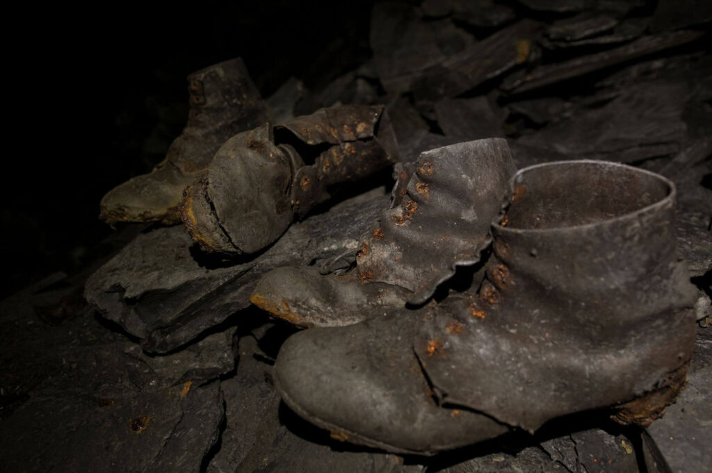 Zu sehen sind zwei Paar genagelte Schuhe. Diese Schuhe wurden vor Jahrzehnten in einem rheinischen Schieferabbau zurückgelassen.