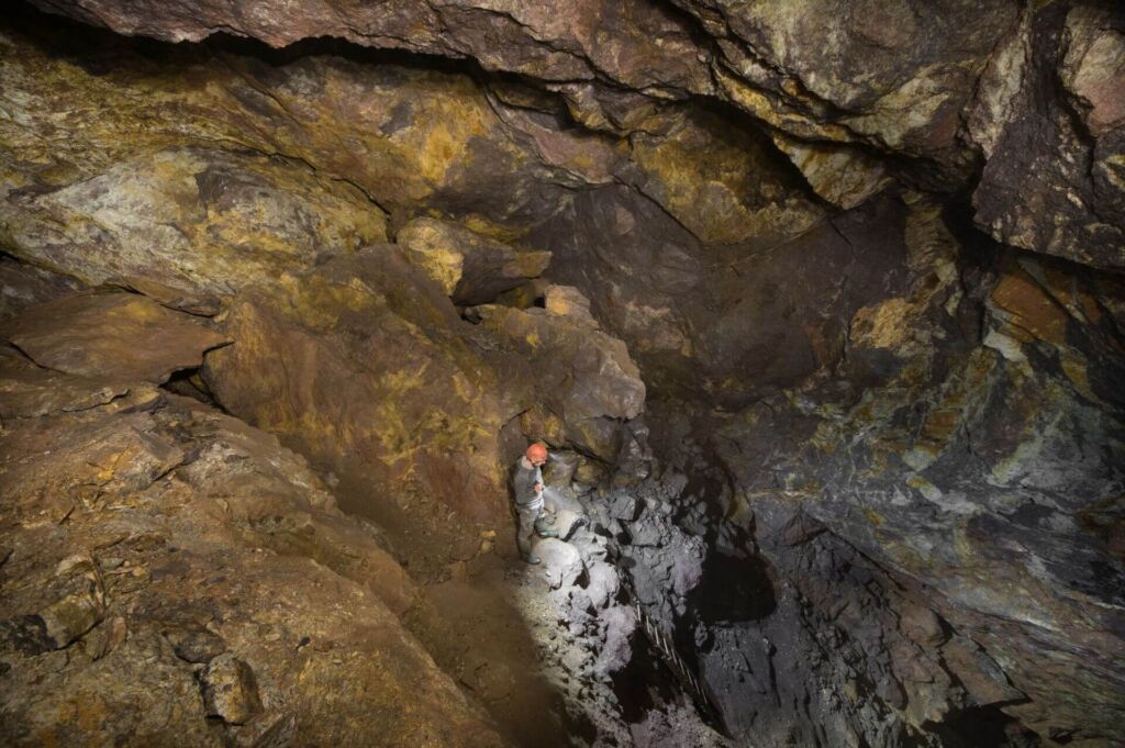 Zeigt eine Person, die im Abbau steht und mit einer Taschenlampe nach unten leuchtet.
