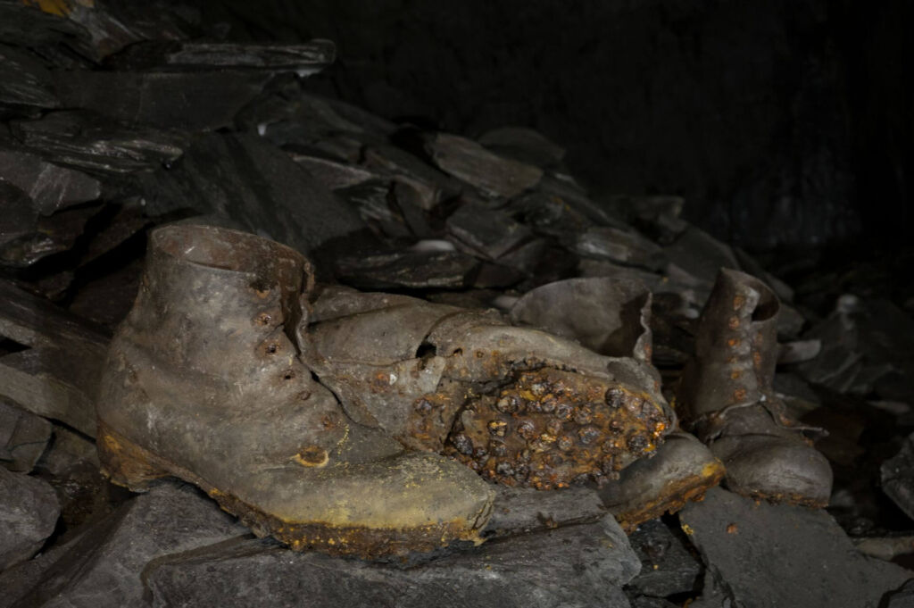 Zu sehen ist ein Paar genagelte Schuhe eines Bergmanns. Diese Schuhe wurden vor Jahrzehnten in einem rheinischen Schieferabbau zurückgelassen.
