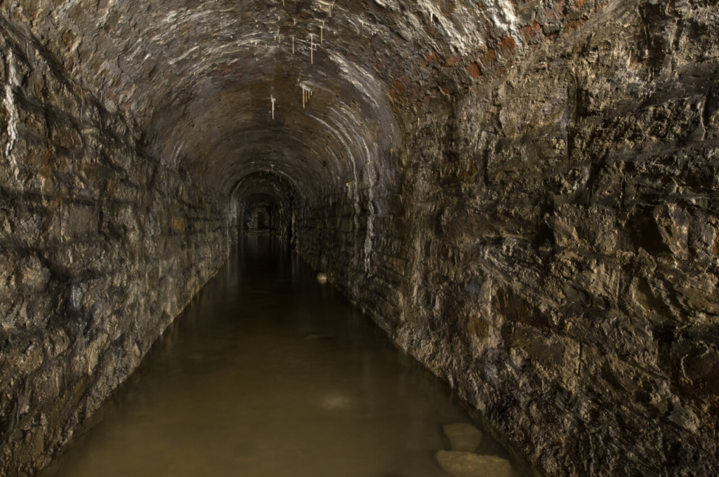 Zeigt den langen Förderstollen in Blickrichtung Grube. Es steht 30 cm Wasser im Stollen.