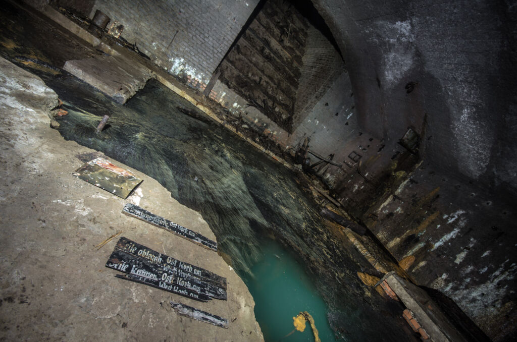 006_foerdermaschinenraum Zeigt den Maschinenraum der Schachtanlage Venusberg. Die Maschinen fehlen und es steht Wasser im Raum.