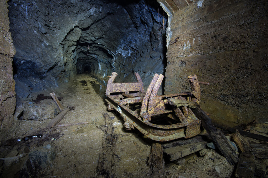 008_lore Zeigt ein rostiges Lorenchassi ohne Räder im Stollen.