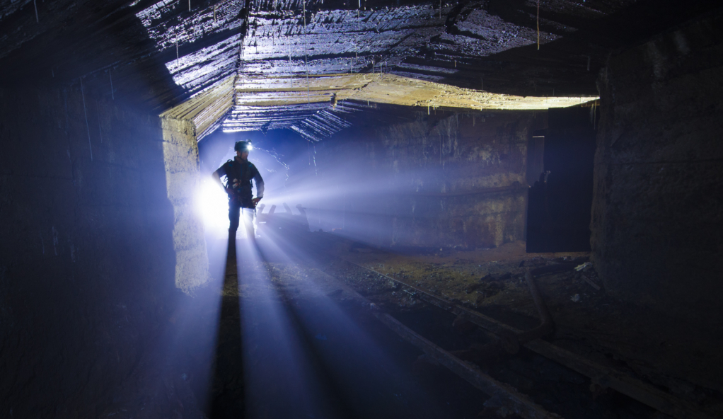 009_rene_im_licht Zeigt eine Person neben einem Lorenchassi. Von hinten strahlt blaues Licht an der Person vorbei.