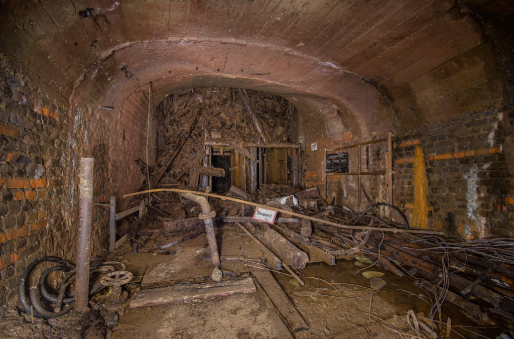 010_blindschacht_16 Zeigt den Blindschacht, mit einem riesigen Berg marodes Holz des Schachtgerüsts darauf.