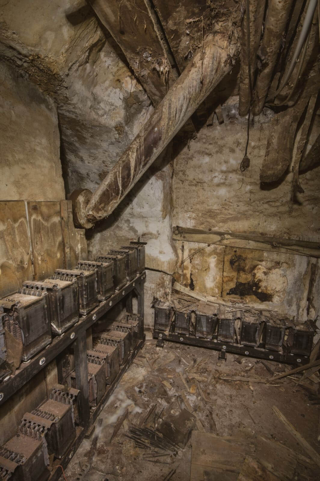 Zeigt alte Bleiakkus auf alten Holzregalen in einer verlassenen Fabrik.