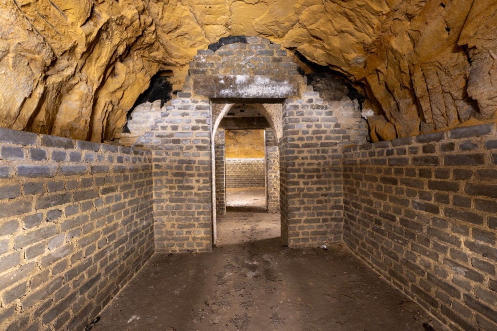 Schutzraum mit nackter Felsdecke und gemauerten Wänden, in einer Kaverne des Südstollens