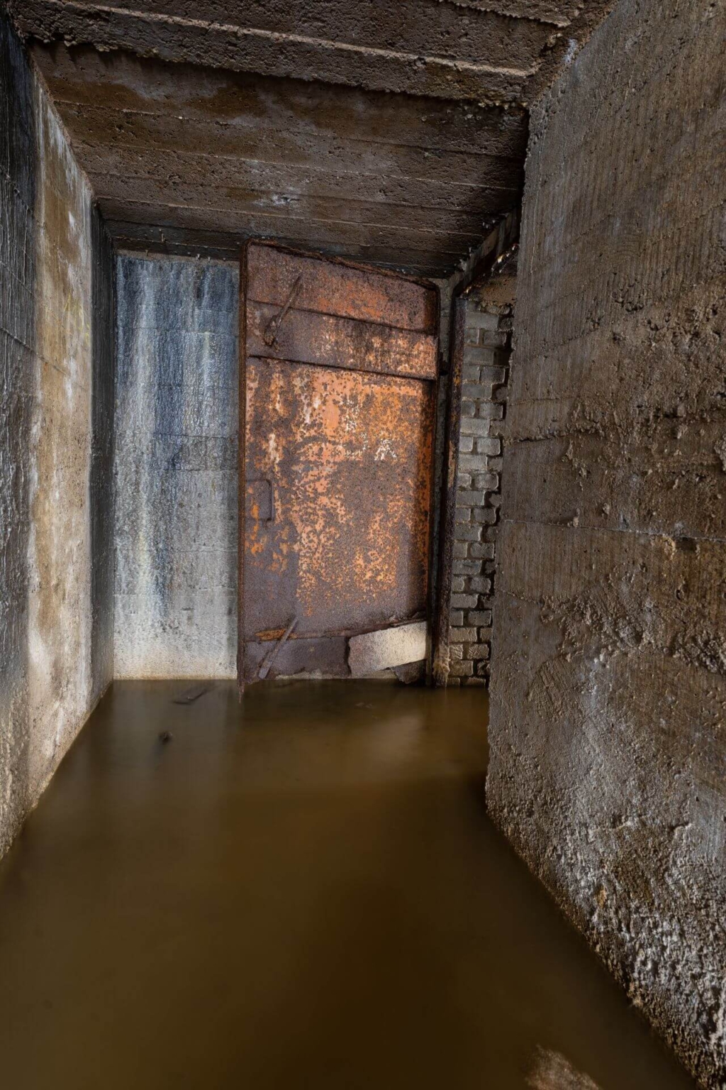 Verrostete Stahltür zum Ausgang, im Stollen steht 30 cm Wasser.