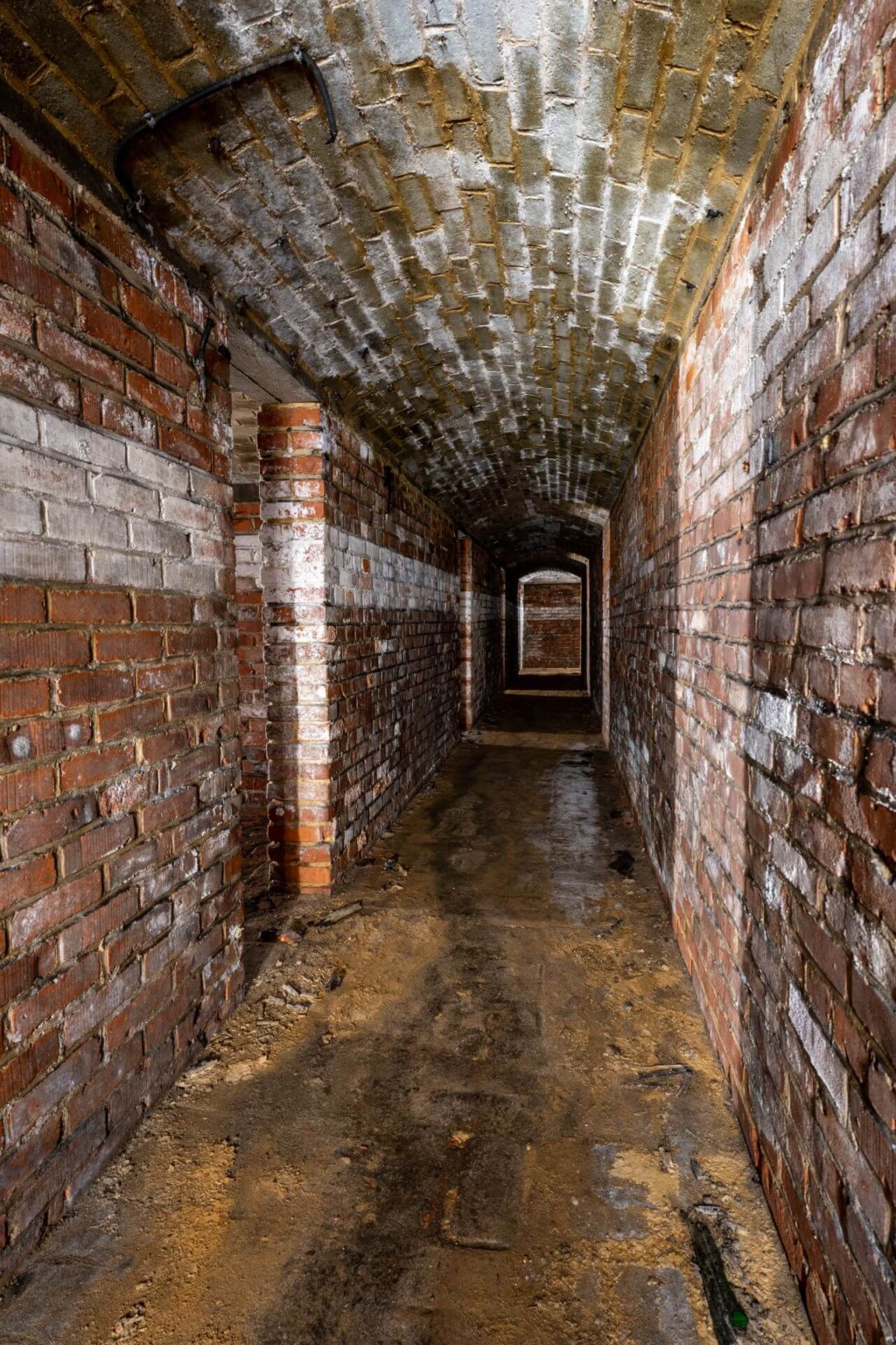 Mit roten Ziegeln ausgemauerter Stollen, links die Türen zu den Schutzräumen.