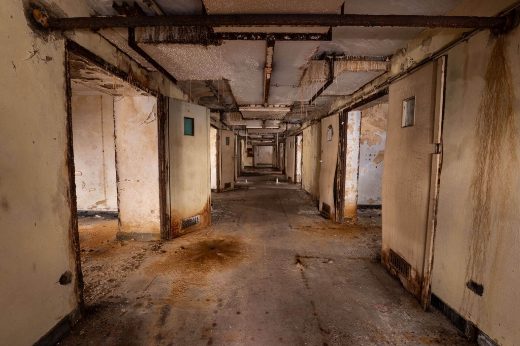 Langer Flur mit Flügeltüren links und rechts zu den Patientenzimmern.