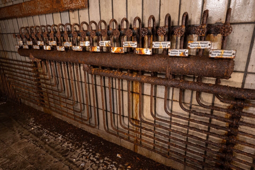 Riesiger Heizungsverteiler mit Wasserhähnen und Emailleschildern.