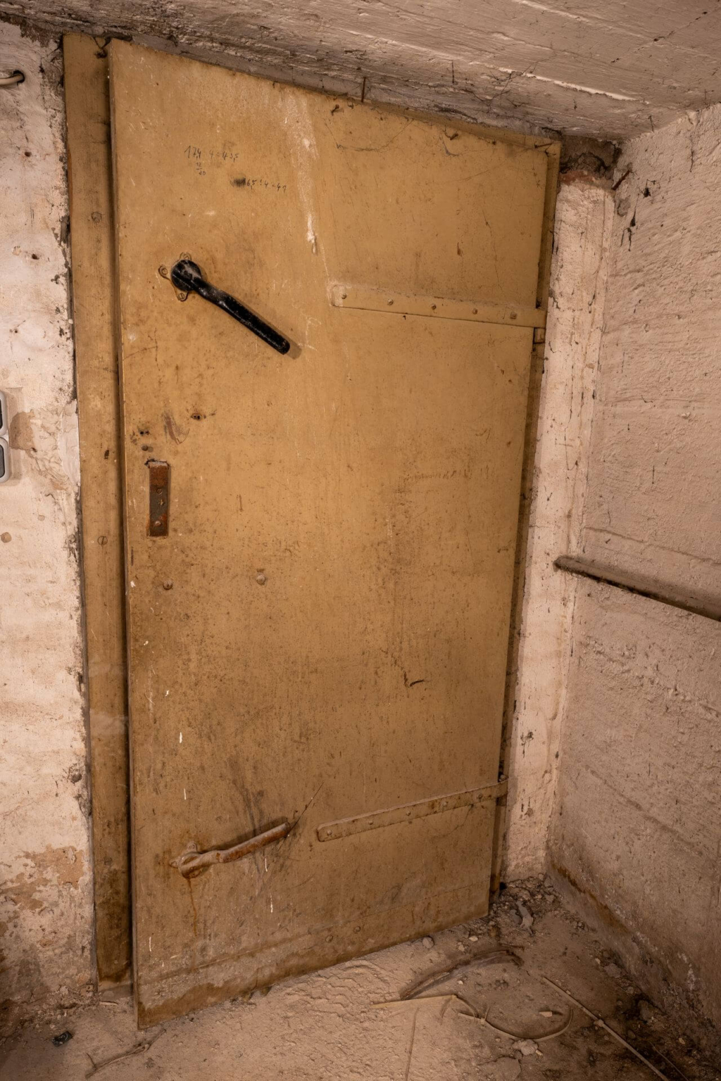 Eine gelbe Luftschutztür aus dem 2. Weltkrieg aus Holz mit Blechbeschlag.