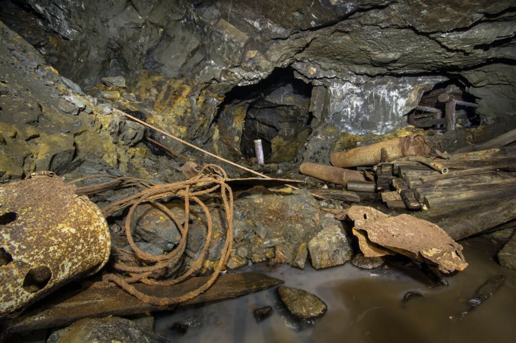 008-altbergbau-abbau-baumaterialien Zeigt viele zurückgelassene Materialien wie Balken, Lüftungsrohre und Stahlseile.