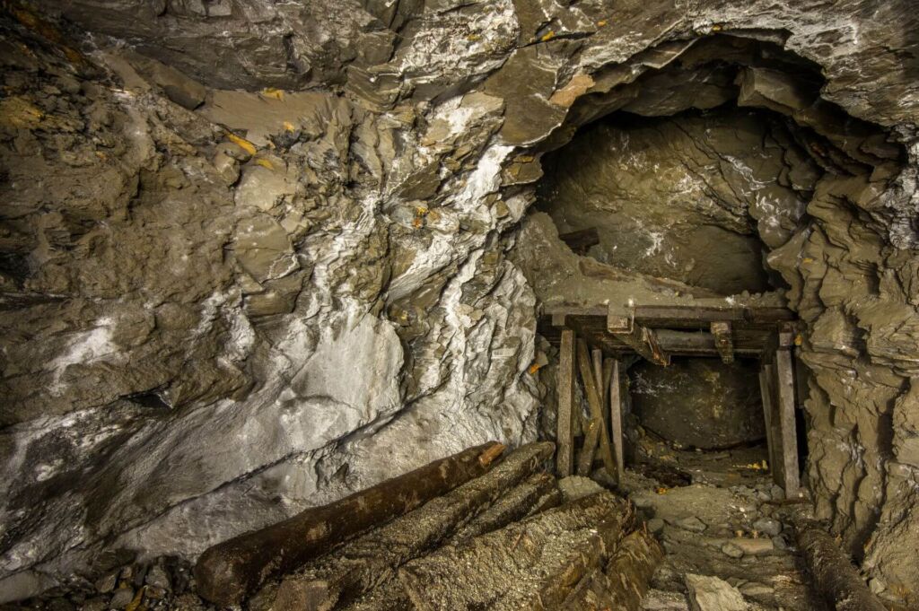 011-altbergbau-holzausbau-schuette Zeigt eine Holzkonstruktion im Stollen, die als Rampe zum füllen der darunter stehenden Lore diente.