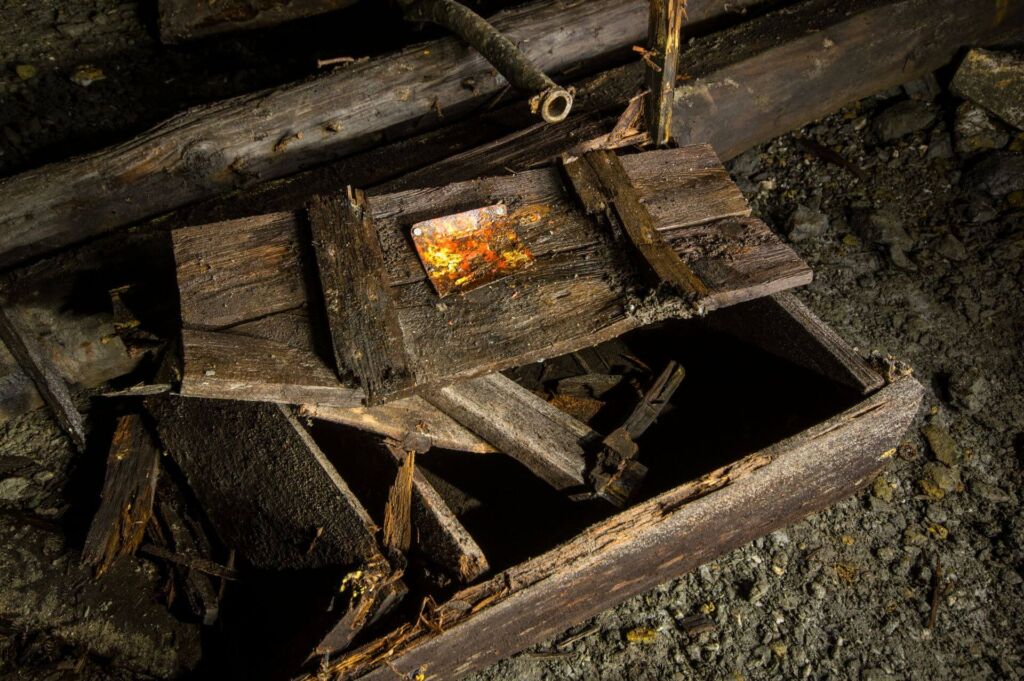 012-altbergbau-sprengstoffkiste Zeigt eine marode Sprengmittelkiste aus Holz mit einem Warnschild aus Metall darauf.