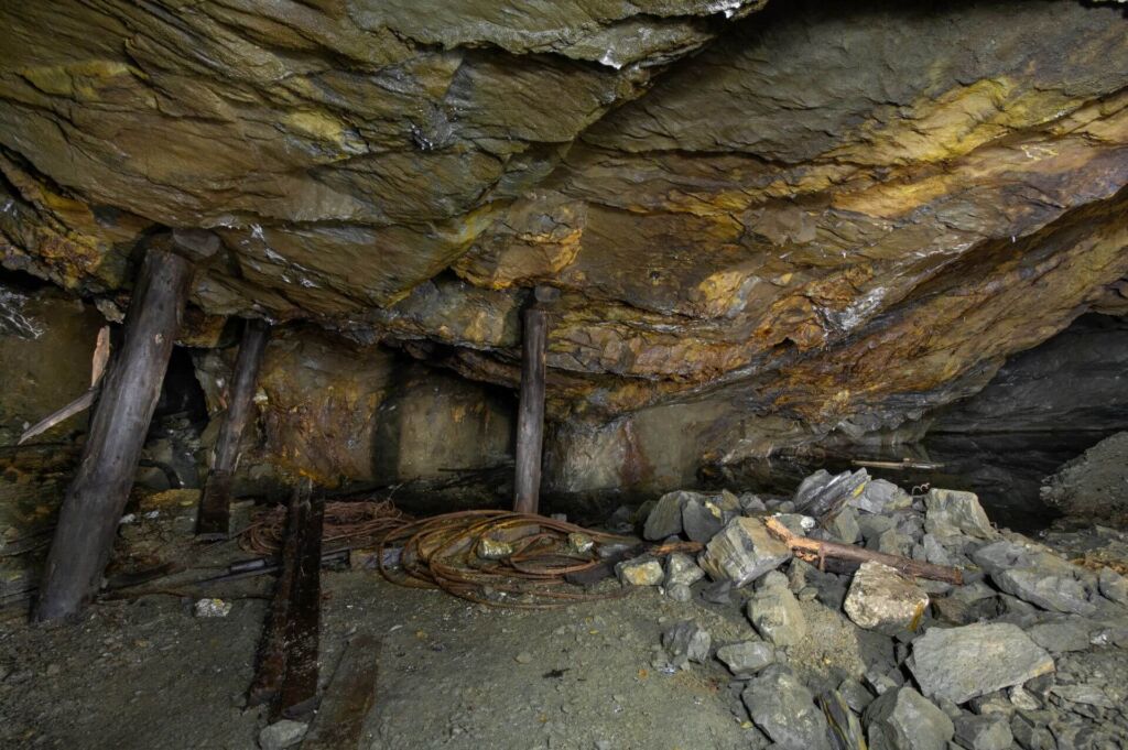 013-altbergbau-abbaukammer-stempel-untertage-see Zeigt Stempel, welche die Firste stützen und im Hintergrund ist ein kleiner untertägiger See.