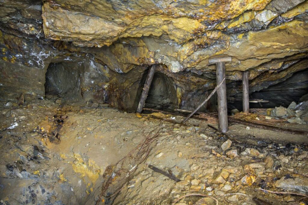 014-altbergbau-eisenerzgrube-stempel-abbau Zeigt einen Rollentrichter, im Hintergrund steht Holzstempel und stützen die Firste.