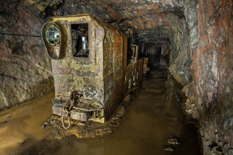 In der stillgelegten Grube Amalienhöhe steht eine verrostete Lore auf einem überschwemmten Schienenweg.