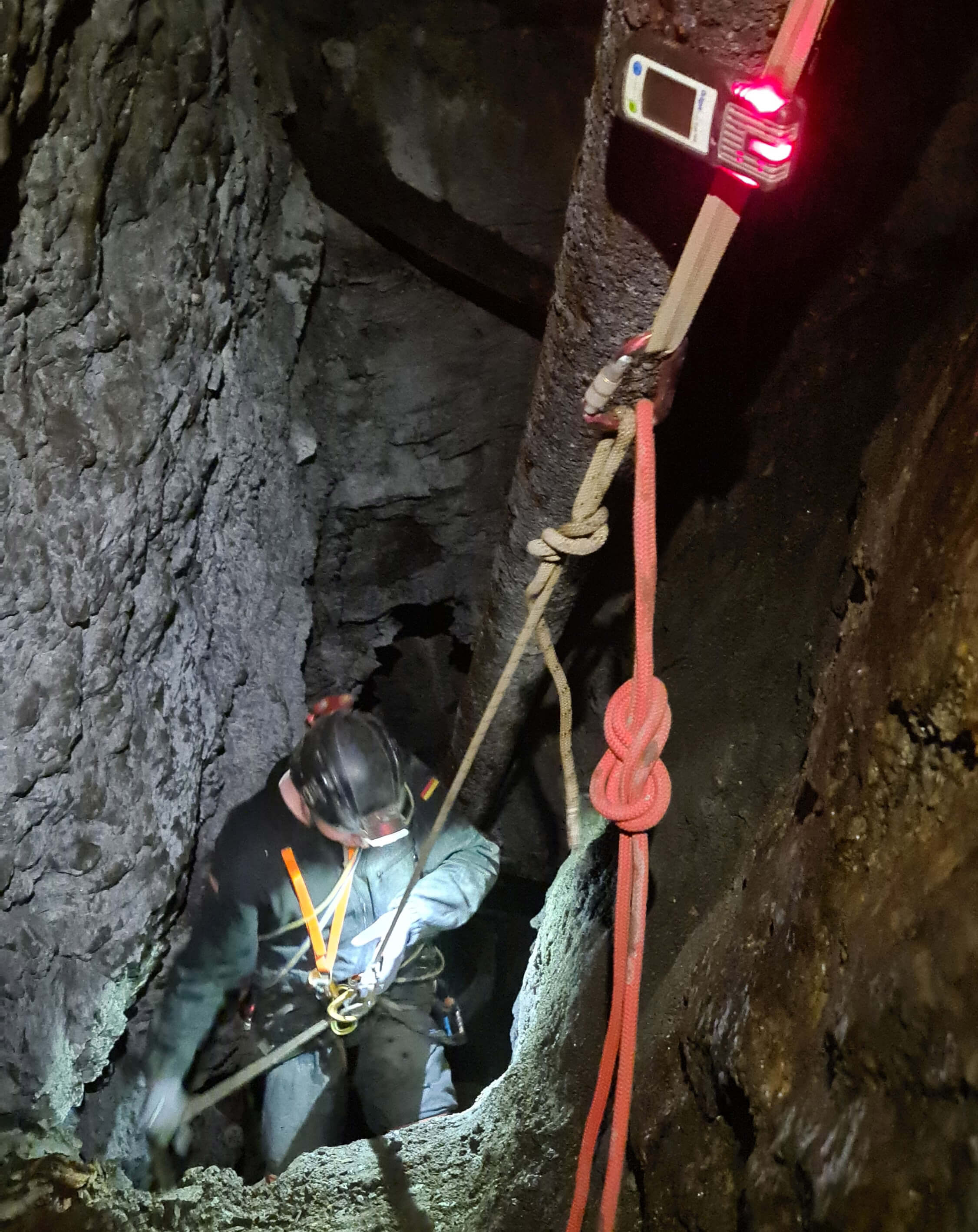 Eine Person seielt sich mittels Seiltechnik in einen Bergbauschacht ab.