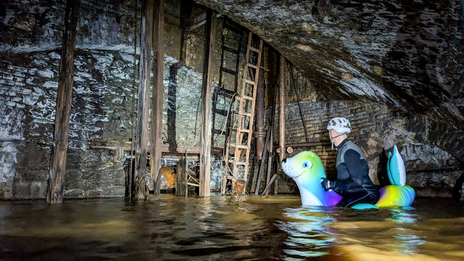 Eine Person schwimmt auf einer aufblasbaren Robbe durch ein stillgelegtes Bergwerk.